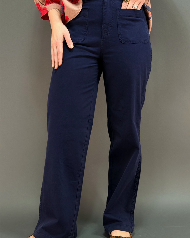 woman wearing dark navy blue wide leg pants in front of a gray background