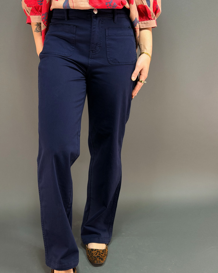 woman wearing dark navy blue wide leg pants in front of a gray background