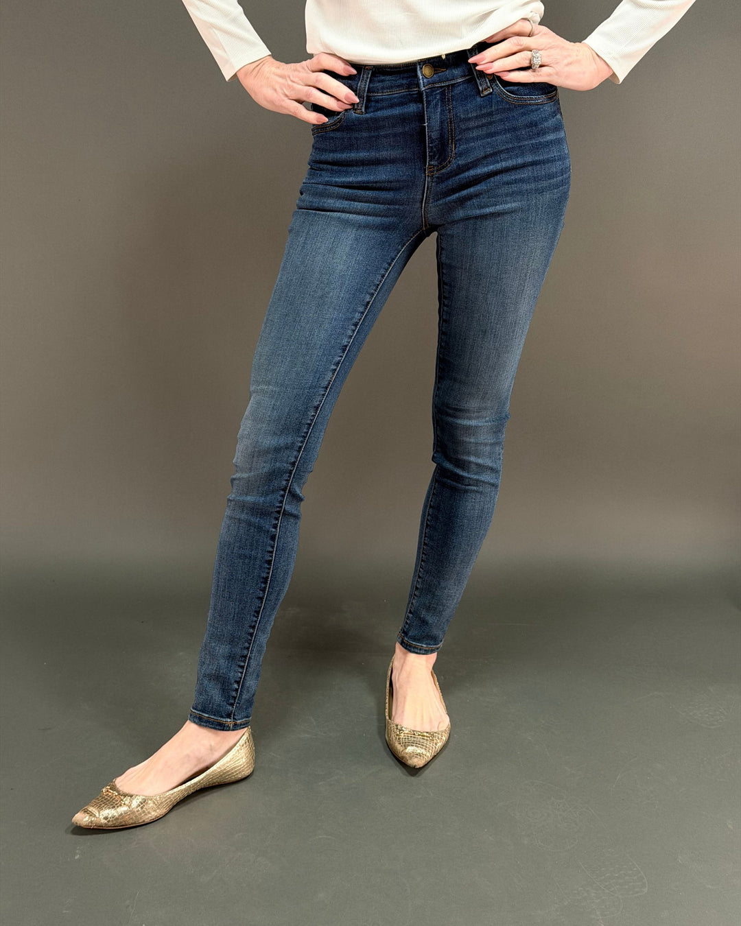 woman wearing dark skinny jean in front of gray background