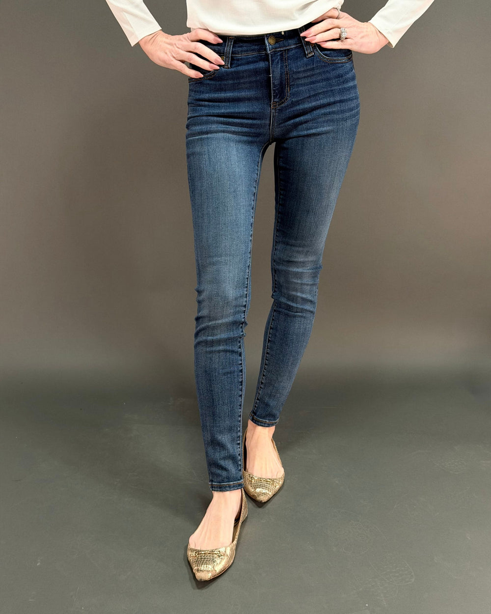 woman wearing dark skinny jean in front of gray background