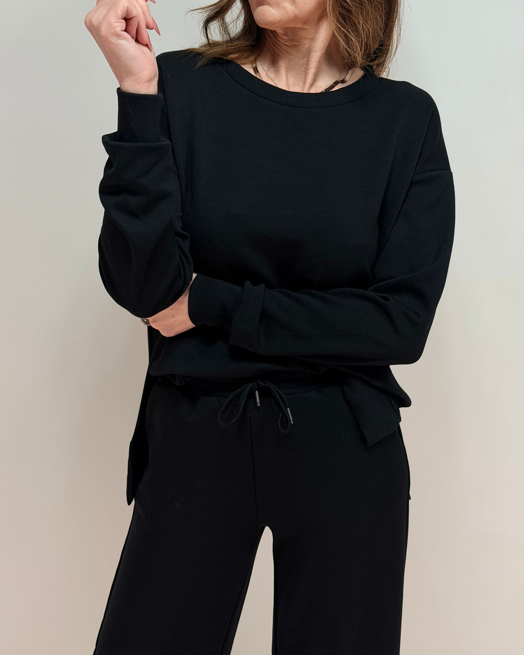Person wearing a black outfit against a plain background