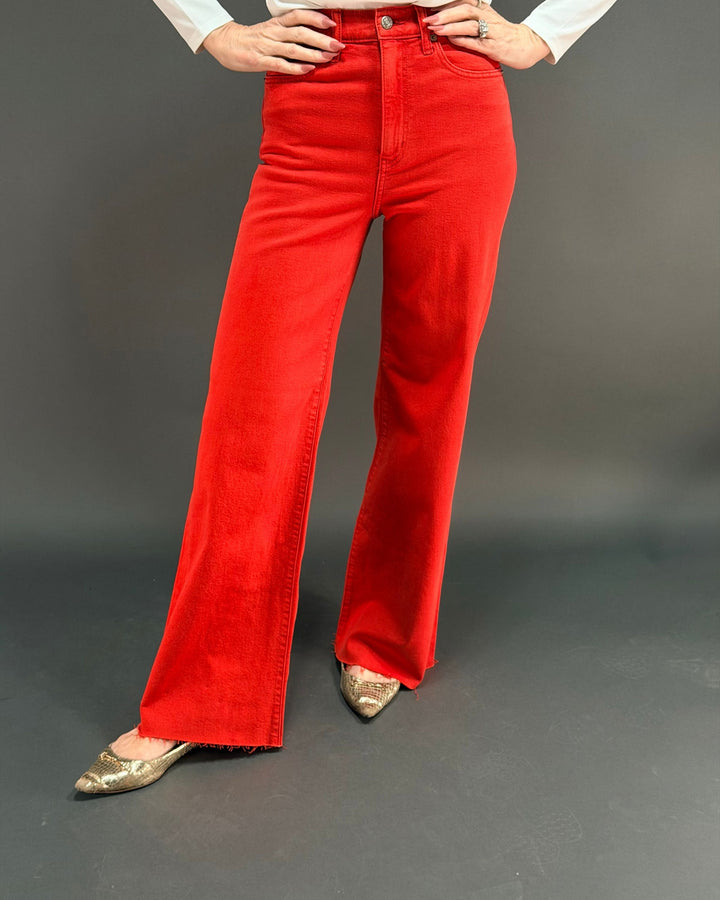 woman wearing red wide leg jean in front of gray background