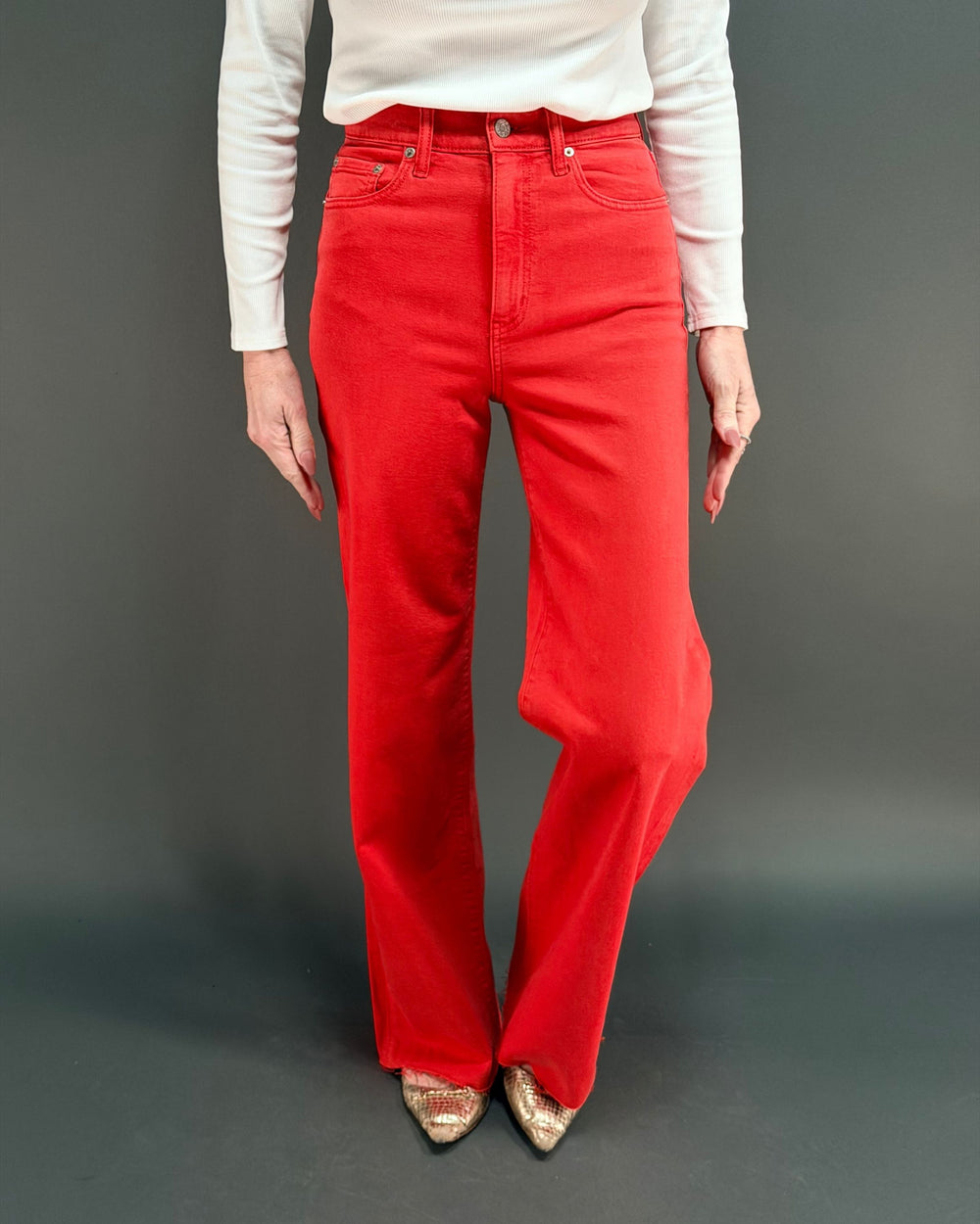 woman wearing red wide leg jean with white shirt in front of gray background