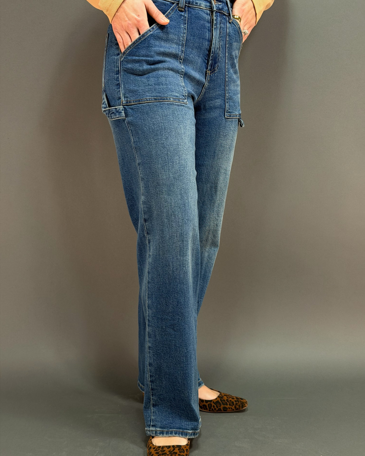 woman wearing wide leg painter style jeans in front of a gray background