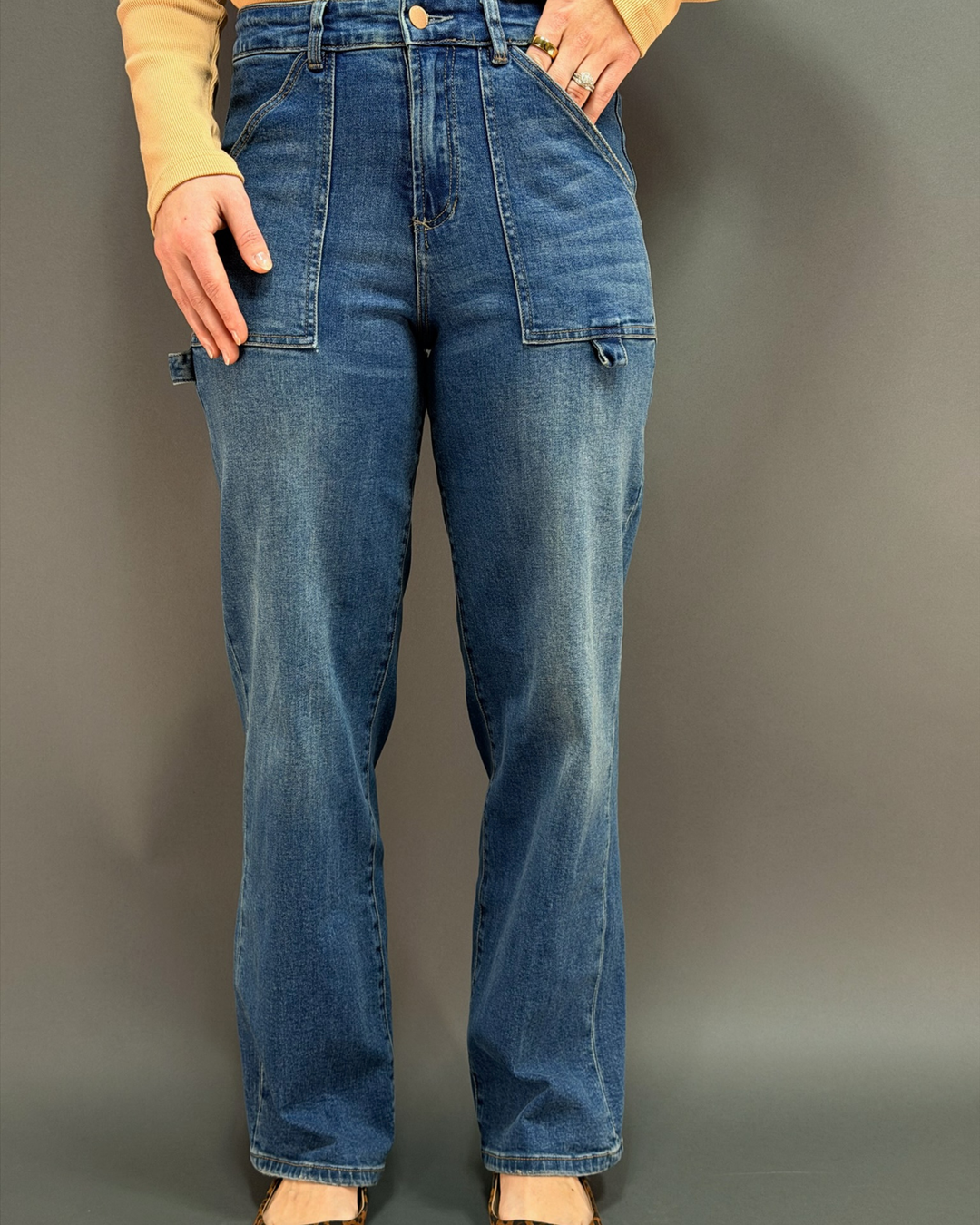 woman wearing wide leg painter style jeans in front of a gray background