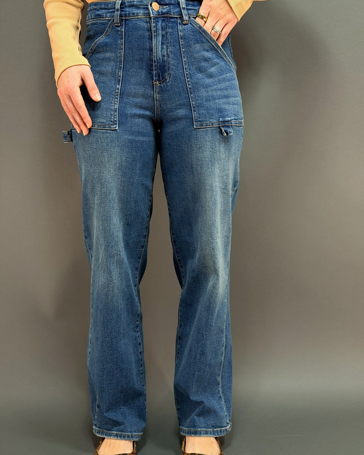 woman wearing wide leg painter style jeans in front of a gray background