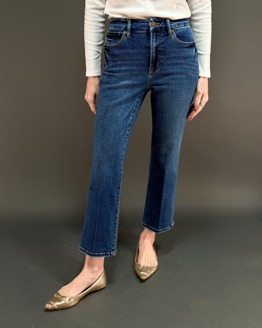 woman wearing cropped flared jeans in front of gray background