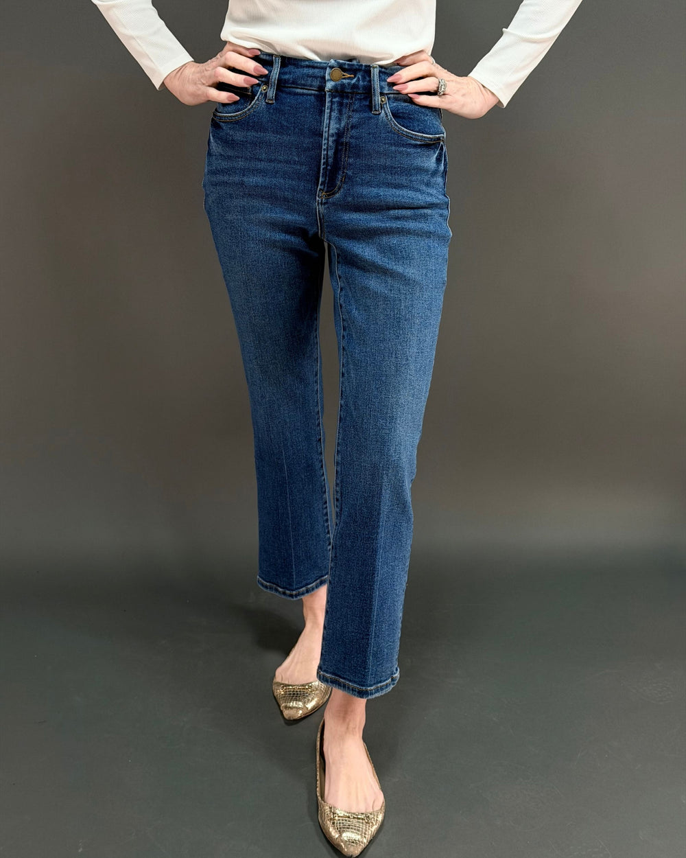 woman wearing cropped flared jeans in front of gray background