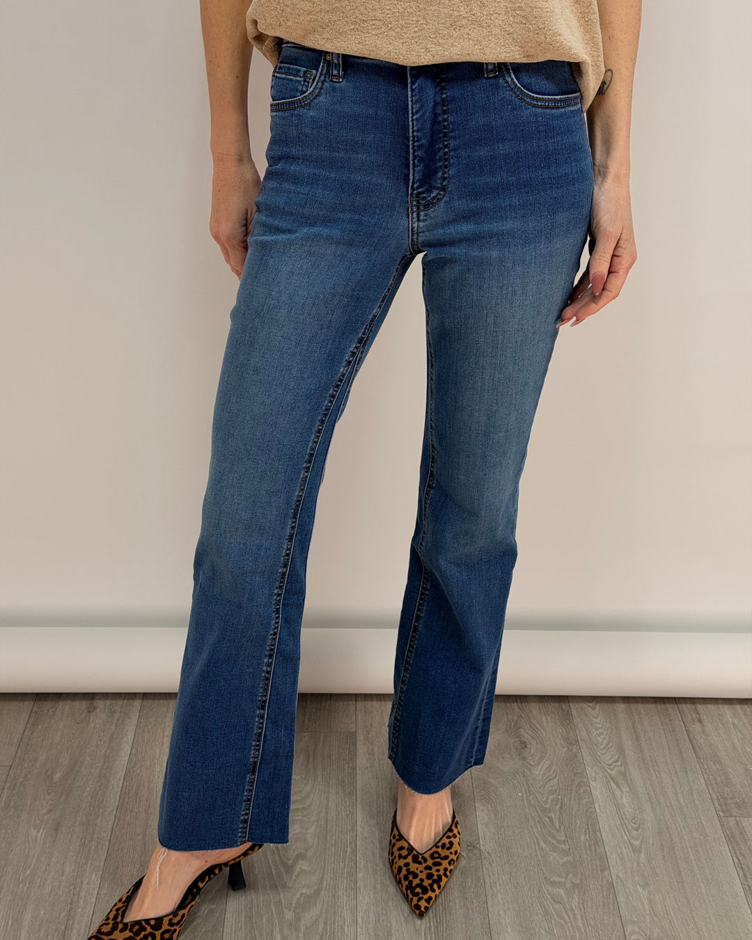 Person wearing blue jeans and leopard print shoes on a plain background