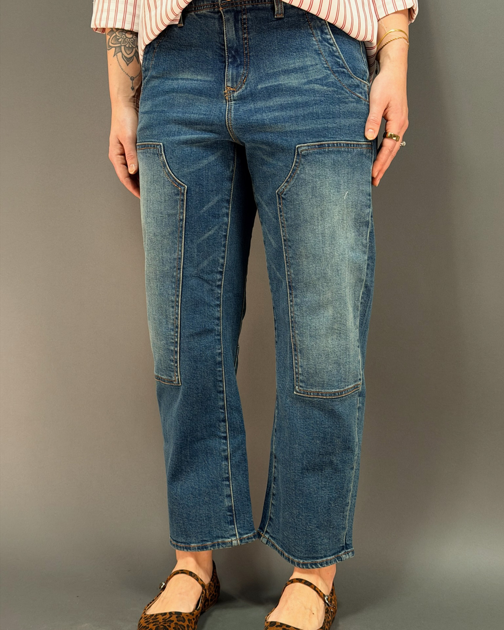 woman wearing barrel leg jean in front of a gray background