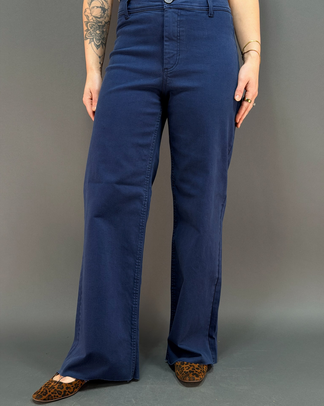 woman wearing navy wide leg pant in front of a gray background