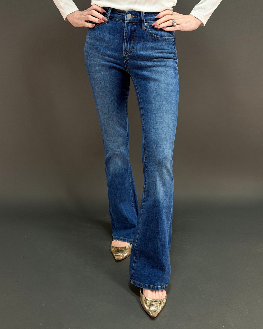 woman wearing flared jeans in front of gray background