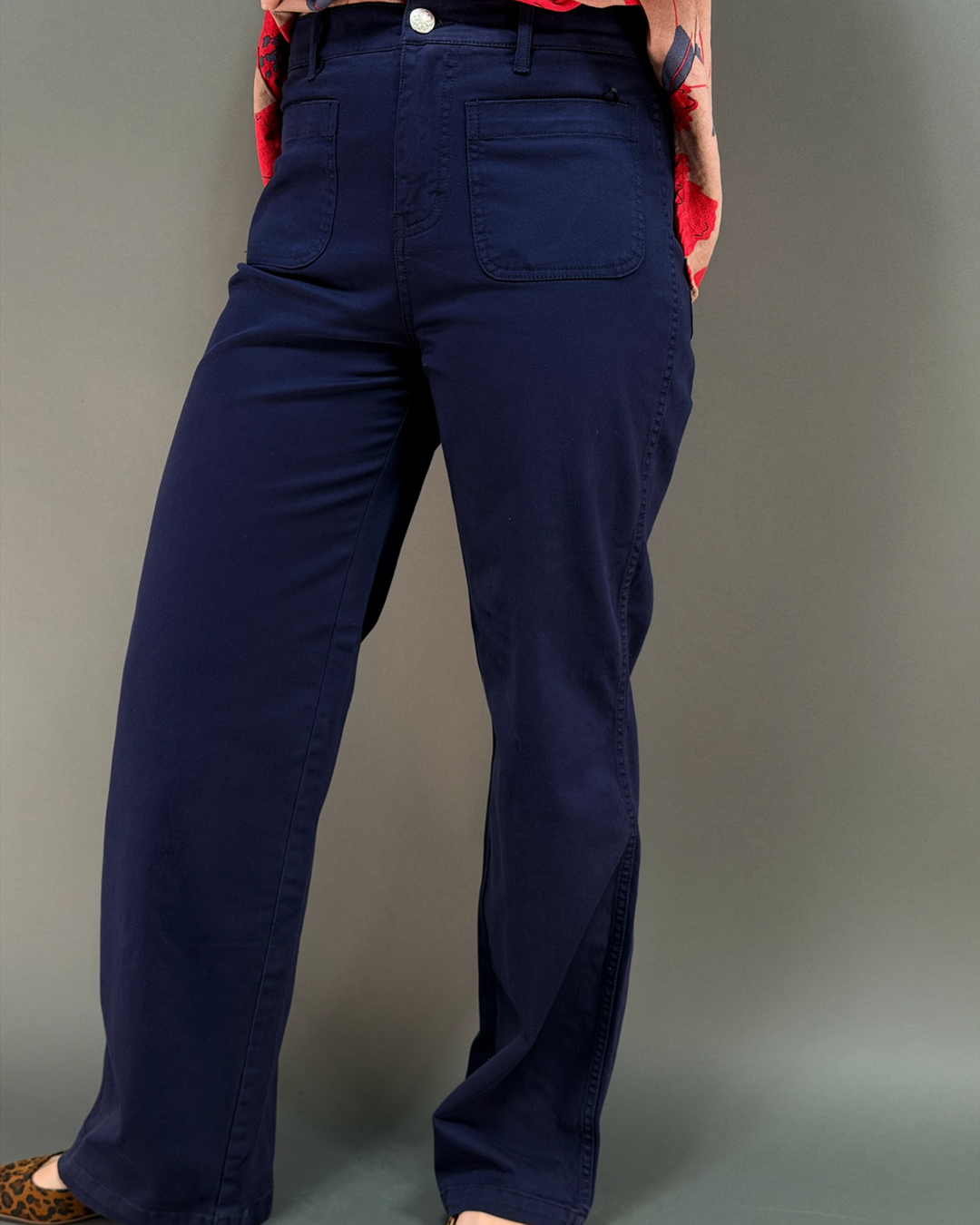 woman wearing dark navy blue wide leg pants in front of a gray background