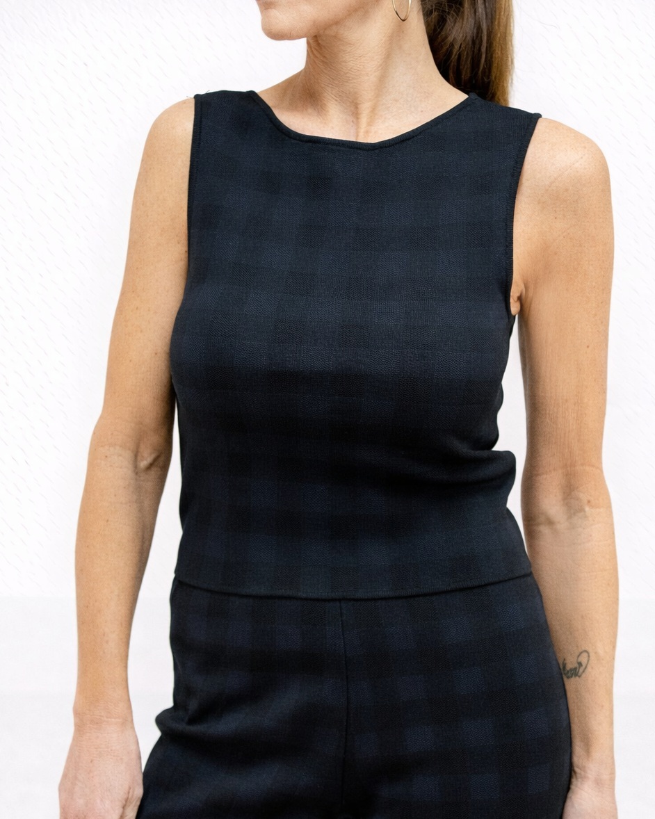 woman wearing navy and black checkered top in front of plain background